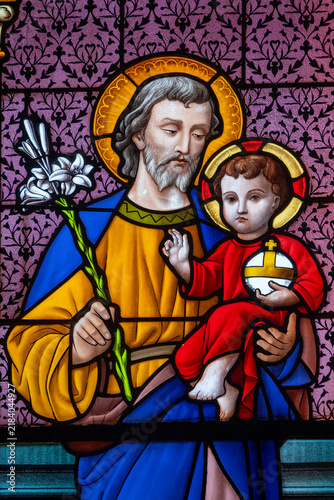Obraz na płótnie A colorful stained glass window depicts Saint Joseph holding the infant Jesus with a lily