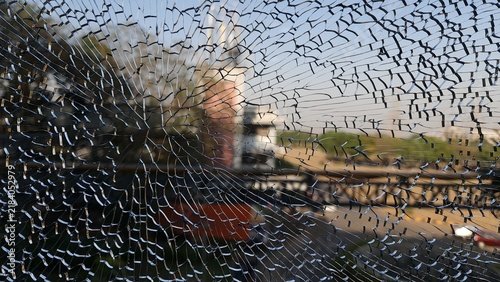 Fotografie Dramatic close up of shattered glass with extensive radial cracks over a blurred