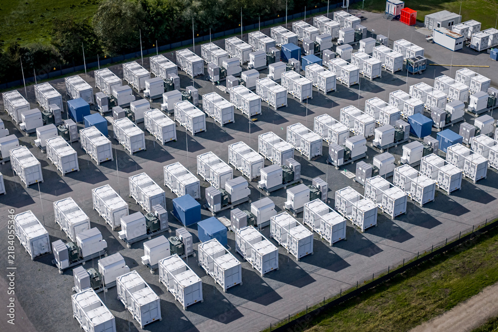 Obraz premium Aerial view of large-scale battery energy storage system (BESS) facility with grid infrastructure in Germany. Rows of containerized lithium-ion battery storage units at a utility-scale energy storage.