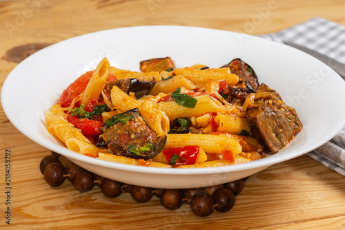 Pasta with eggplants, tomatoes, basil and grated cheese, front view