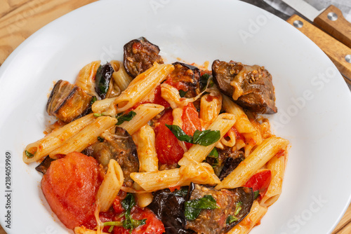 Pasta with eggplants, tomatoes, basil and grated cheese close-up