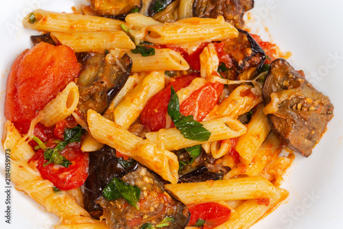 Pasta with eggplants, tomatoes, basil and grated cheese close-up