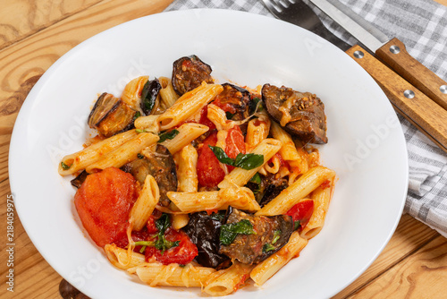 Pasta with eggplants, tomatoes, basil and grated cheese close-up
