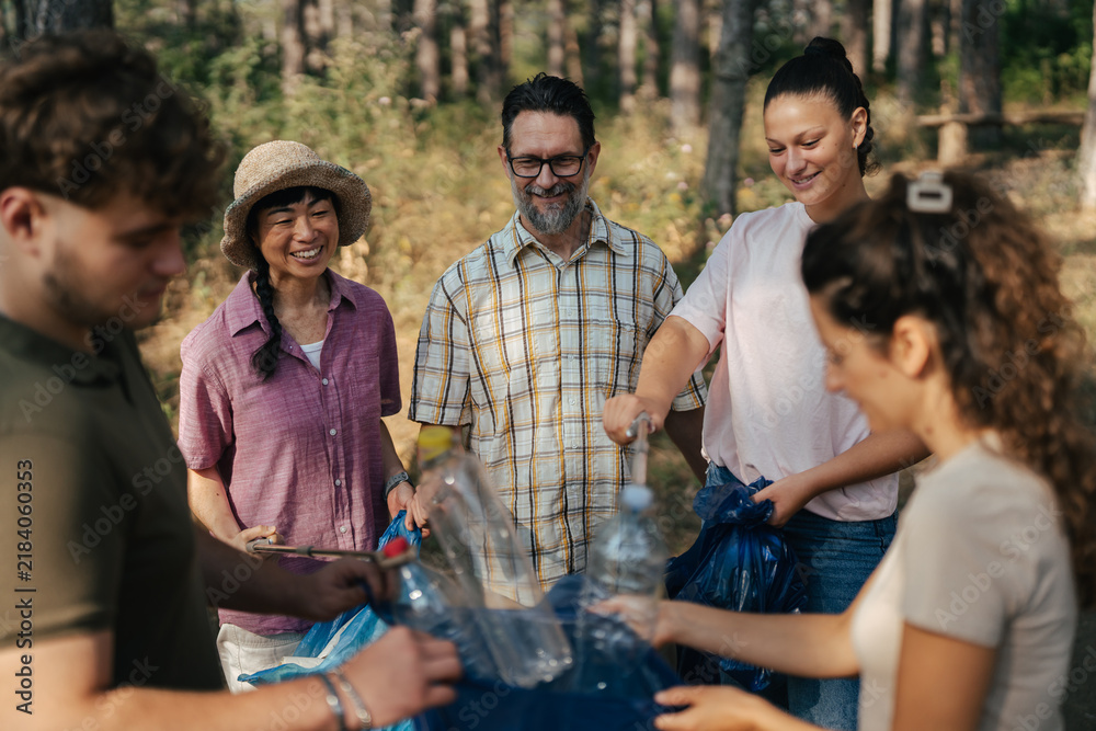 Obraz premium Diverse volunteers collaborating recycling plastic bottles in nature park