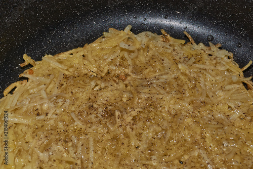 фотографія Large grated potato fritter cooking in a frying pan
