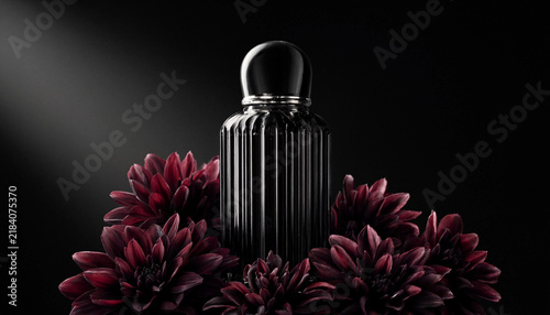 Luxury perfume bottle surrounded by dark red dahlia flowers on a black background