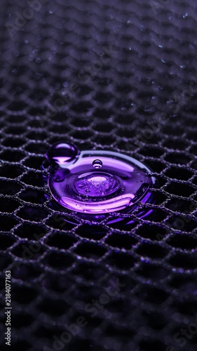 Graphene mesh with violet liquid spreading across hexagonal lattice surface