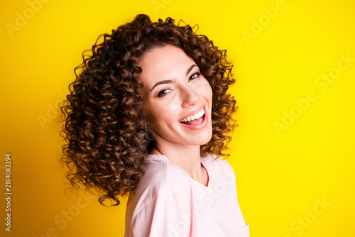 Foto Smiling woman with curly hair laughing in front of a bright yellow background, c