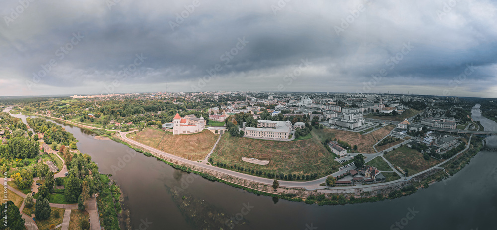 Obraz premium Aerial panorama of a riverside old town with historic buildings under dramatic clouds