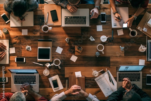 Overhead view of a diverse team collaborating around a rustic wooden table in a modern office space