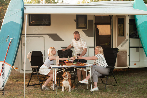 фотографія A happy family is resting nearby near their motorhome in the forest