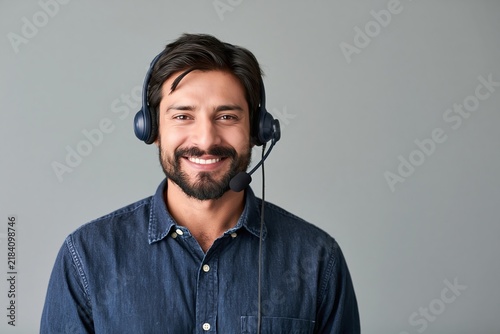 Friendly customer support agent wearing a headset and denim shirt smiling against a grey background