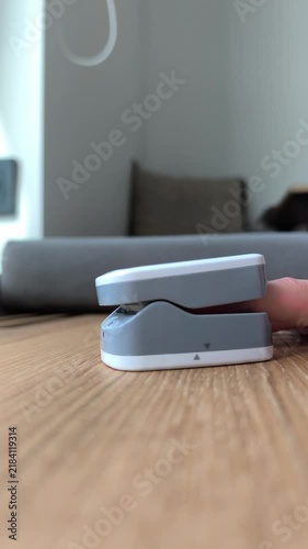 Finger inserted into pulse oximeter device measuring heart rate and oxygen. Person uses handheld medical monitor at home to check pulse levels. Health device rests on wooden table in