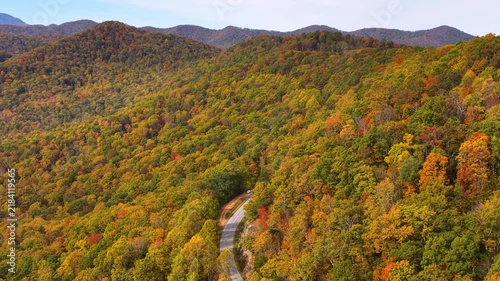 Peaceful roadside overlook in Tennessee Appalachians with parked car facing vibrant autumn scenery and endless forested mountain ridges.