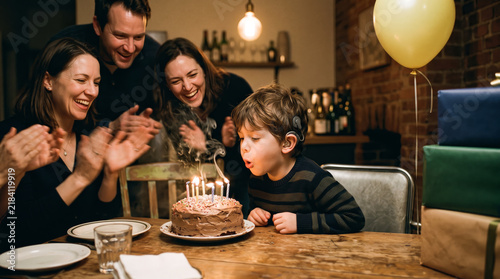 Family celebrating birthday party with deaf child blowing candles