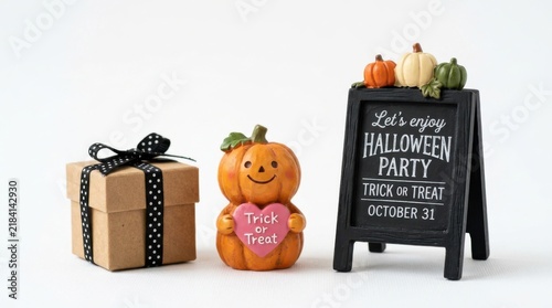 Halloween party table decor with gift box, pumpkin figurine, and chalkboard sign isolated on white background