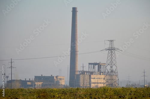 фотографія pipes and power plant building in the rays of the sun at sunset