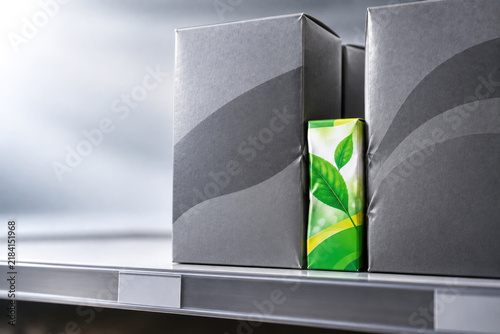 Green leaf package stands between large gray boxes. Space for text.