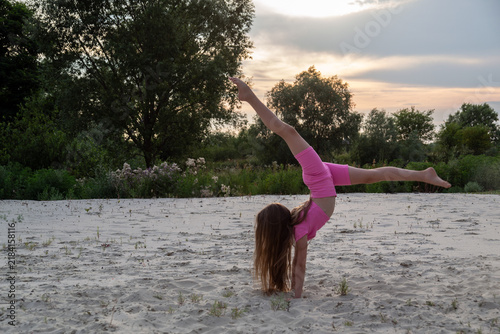 Fotografie Young gymnast training outdoors at sunset