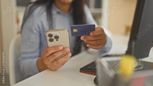 Woman holding smartphone and creditcard in hands at office building desk, tapping phone for payment and showing card chip; convenience.