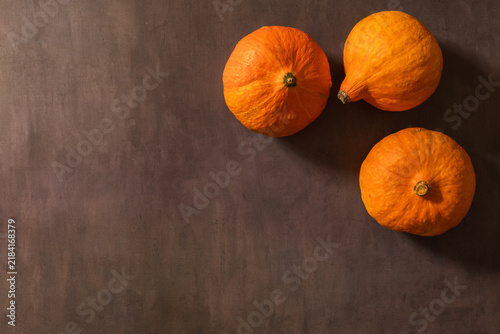 Still life with pumpkins on a brown background. Three orange pumpkins, minimalist style.