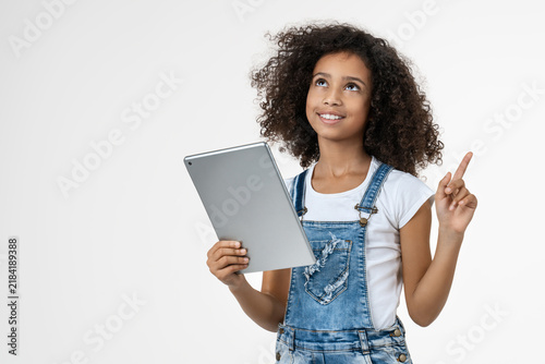 Little African girl having an idea while holding digital tablet isolated on white background, smiling child with touchscreen device, education, technology, learning, inspiration concept