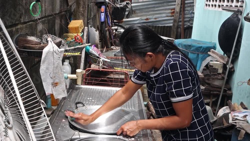 A woman washes dishware in an outdoor sink