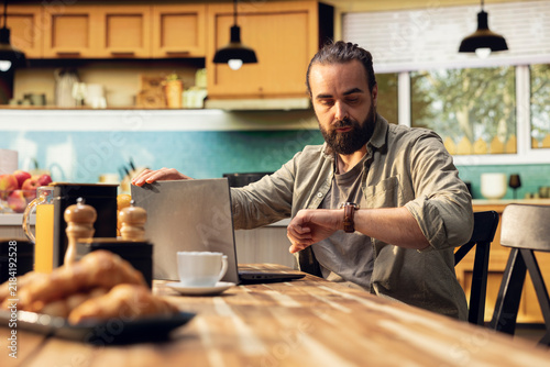 Canvas Print Worker checks his wristwatch while running late for the office, preparing to leave home quickly and avoid a delay during the morning routine