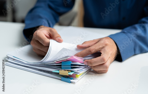 Close-up of professional businessman hands searching financial document files with colorful sticky notes at office desk. Male employee organizing corporate paperwork and business audit concept.