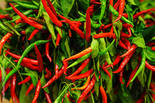 Chili peppers hanging together in a display at a market in the evening