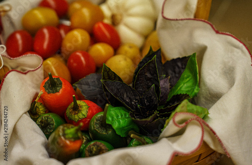 Variety of fresh vegetables and fruits in a basket with a white cloth