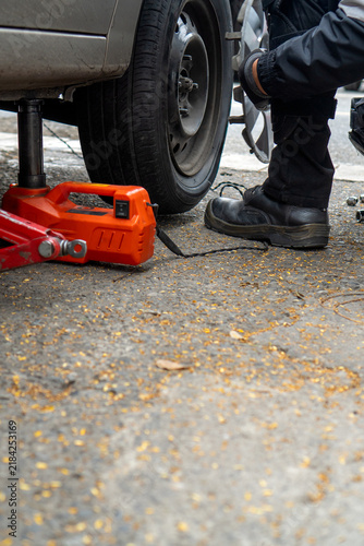 Fotografie Person changing car tire on road