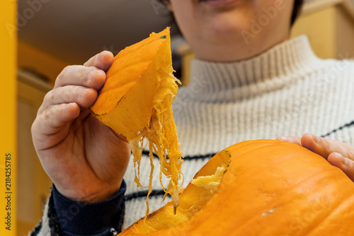 Foto Person scooping fibrous pulp from carved orange pumpkin