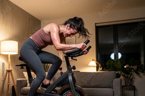 Side View of Fit Young Woman Holding Towel and Cheering Victory on Stationary Bike, Daily Indoor Fitness Routine
