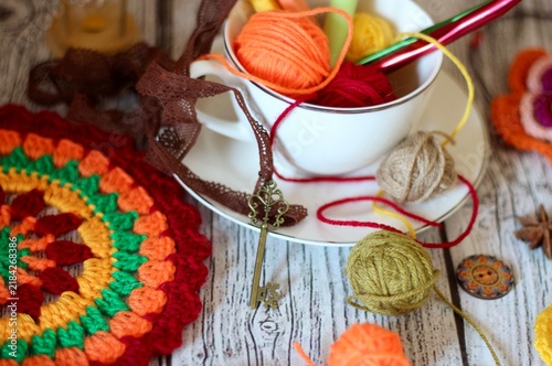 A cozy autumn‑winter still life on the table with a cup, balls, hooks, and various feminine items — a bright photo
