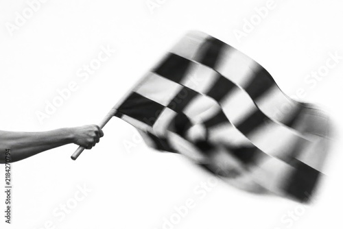 Person holding waving checkered flag in dynamic motion, black and white photography, sports event finish line, victory, triumph, motion blur effect