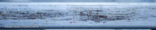 Horizontal close up of heavily scratched rusty metal bar texture.A high-resolution, panoramic-style close-up shot focusing on a weathered horizontal silver or grey painted metal bar. 