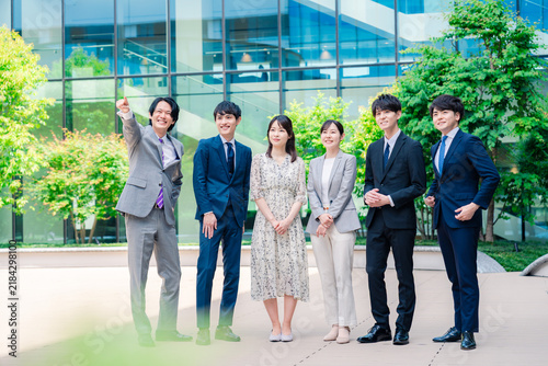 オフィス街で斜め上を指差すビジネスパーソン集合写真