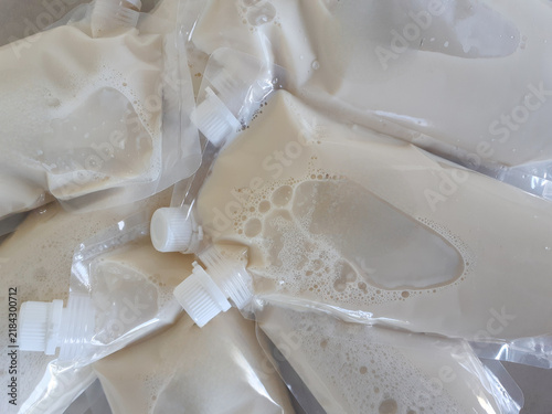 Several clear plastic spouted pouches filled with a milky beige liquid, showcasing modern drink packaging
