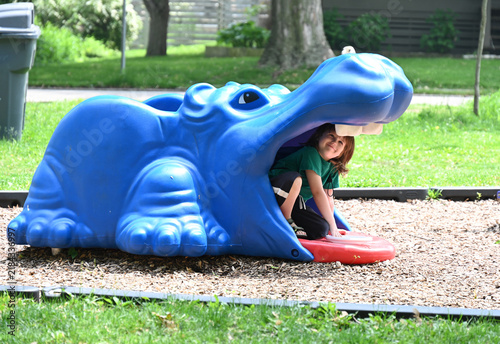 Child playing inside a blue hippo on a playground