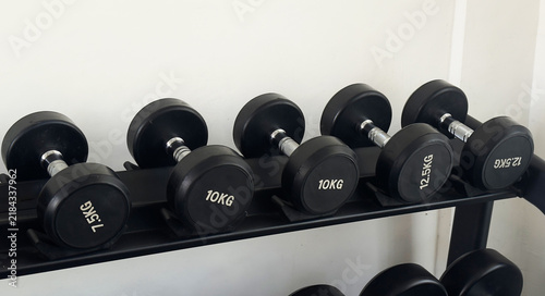 Foto Black dumbbells of different weights arranged on a storage rack in a modern gym