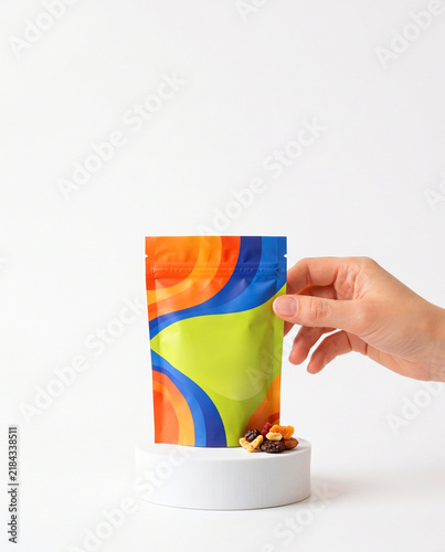 Hand Holding Colorful Stand-Up Zipper Pouch with Dry Fruits on Podium
