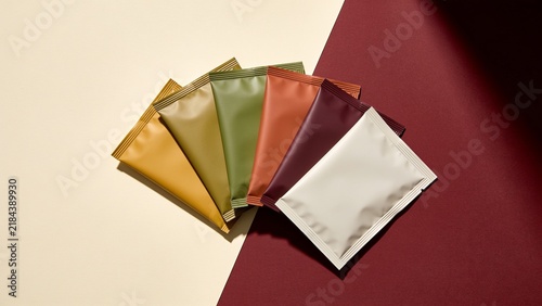 Colorful stack of tea bags arranged on a maroon and white gradient background