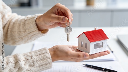 Person holding house key model symbolizing home ownership or real estate success
