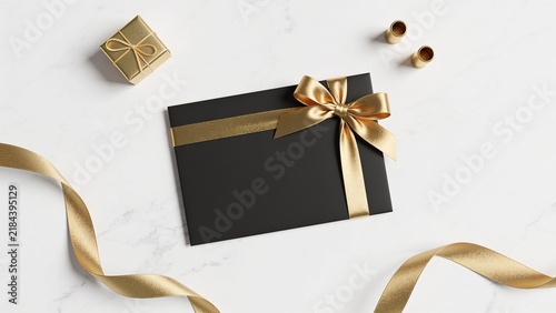 Elegant gift box with gold ribbon and bow on white marble surface