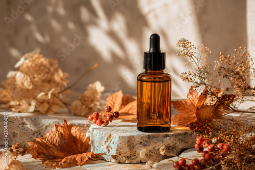 Amber Glass Cosmetic Serum Dropper Bottle with Dried Autumn Leaves in Warm Natural Sunlight.