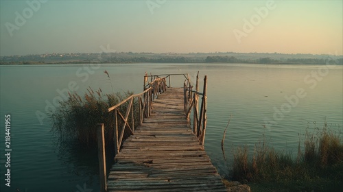 Weathered wooden pier stretching out into calm water at sunrise