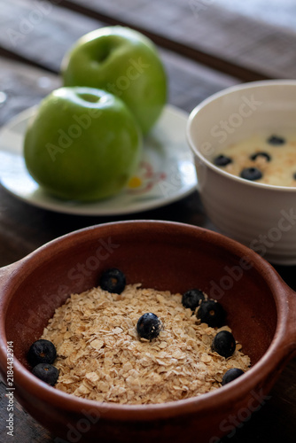 A healthy breakfast in a rustic kitchen setting, served on a weathered wooden table: oatmeal, fresh fruit, and yogurt