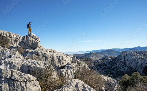 Young man standing on rocks and looking into the distance, limestone rock formations, El Torcal Nature Reserve, Torcal de Antequera, Province of Malaga, Andalucia, Spain
