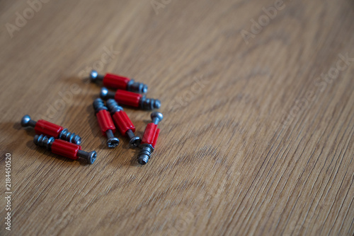 Red furniture connector screws on wooden surface